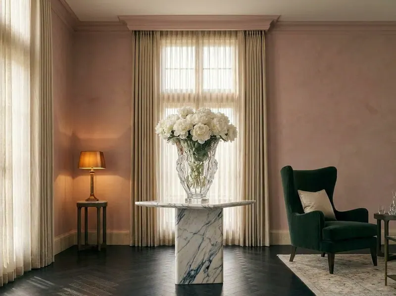 Ultra-luxury drawing room with dusty rose plaster walls, crystal vase with white peonies, deep forest green armchair — Quiet Luxury Colour by Beverly Hills Luxury Interiors