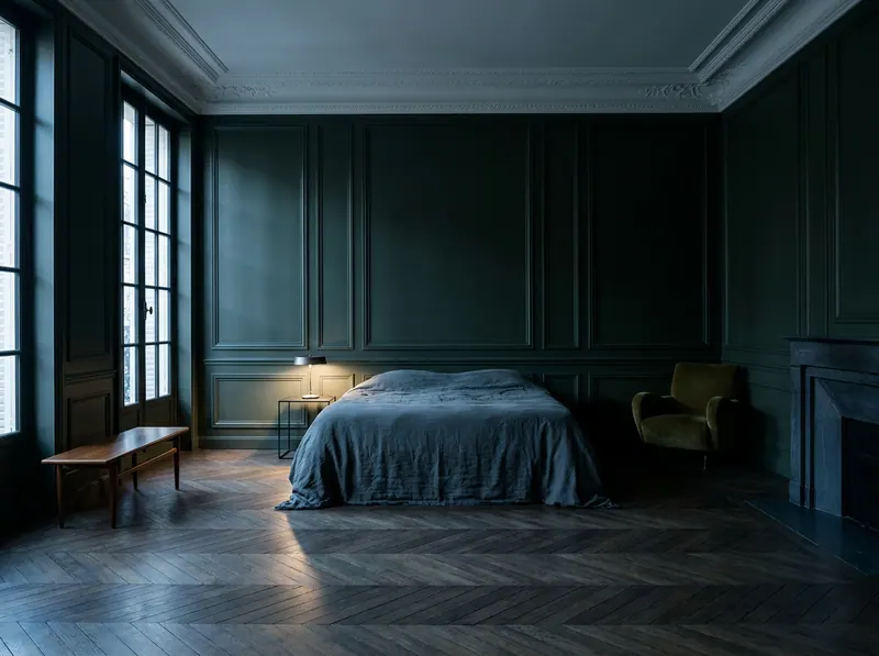 Circadian lighting in a principal bedroom at dusk — deep forest green boiserie, cool twilight through steel casements and a single shielded low-level lamp, specified by Beverly Hills Luxury Interiors
